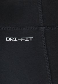 Black athletic leggings featuring a smooth texture, stretchable fabric, and white "DRI-FIT" logo; visible stitching along seams.