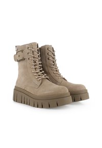 Botines de ante beige con cordones en el frente, cremallera lateral y suela de plataforma gruesa con estrías verticales. Detalle de hebilla en el lado.