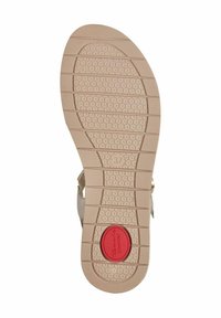 Semelle de sandale beige clair avec une surface texturée, des motifs circulaires, et un logo circulaire rouge au centre. Taille marquée comme 37.