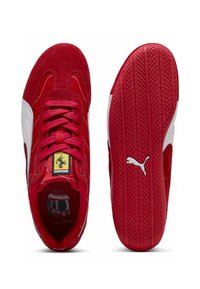 Rote und weiße Puma Ferrari Wildlederschuhe, einer zeigt die Oberseite mit Schnürsenkeln und Logo, der andere zeigt die rote Sohle mit Puma-Logo.