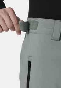Grijze broek met een gladde textuur, voorzien van een haak-en-lus sluiting aan de taille en een ritszak aan de zijkant.
