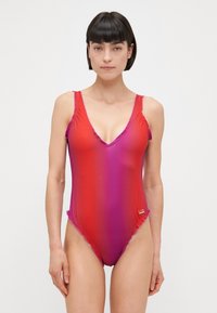 Μονοκόμματο μαγιό σε γραδίσιο κόκκινο προς μωβ. Διαθέτει V-λαιμόκοψη, φουσκωτές τιράντες και λογότυπο στο πλάι. Φτιαγμένο από απαλό, ελαστικό ύφασμα.