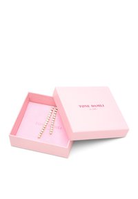 Roze geschenkdoos met het etiket "TONE DAMLI by A&C" bevat twee metalen haarclips met afwisselend heldere en gekleurde strassteentjes.