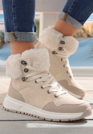 Beige Wildlederstiefel mit flauschigen weißen Bündchen, Schnürdesign und grauen Akzenten. Texturierte Oberfläche und weiße Sohle mit gemustertem Profil.