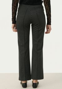 Uitlopende zwarte broek met een streepjespatroon, met een hoge tailleband en twee achterzakken. Subtiele textuur en een op maat gemaakte pasvorm.
