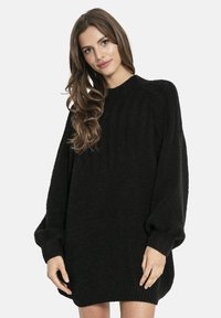 Czarna dzianinowa sukienka swetrowa z prążkowaną struktur�ą, okrągłym dekoltem i oversize'owymi balonowymi rękawami. Tkanina wydaje się miękka i gruba.