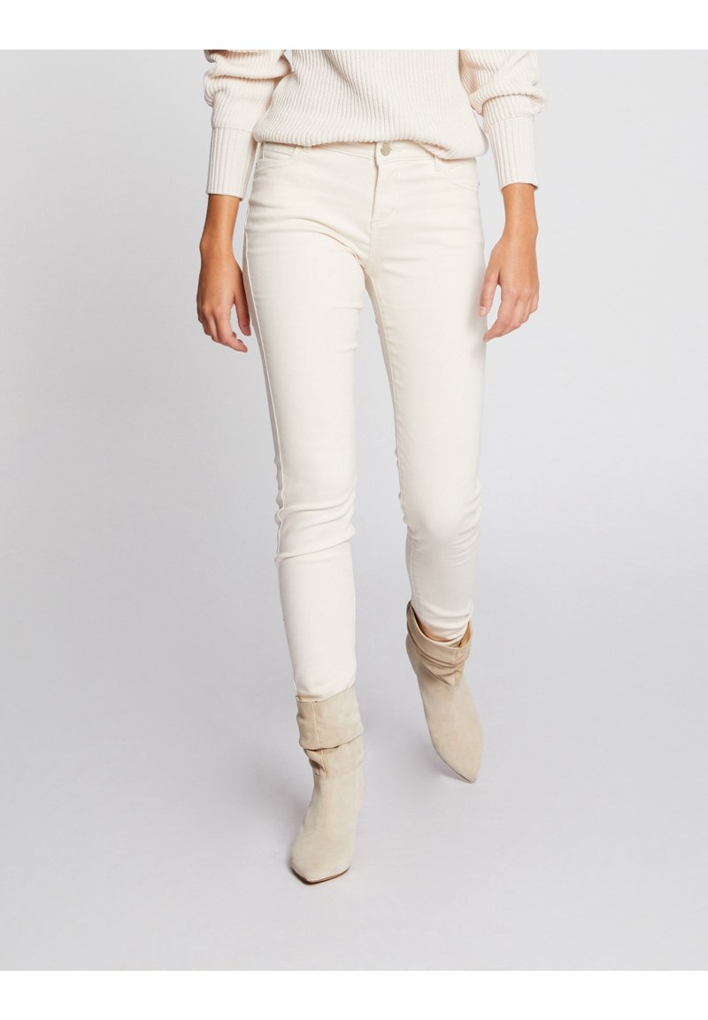 Jeans blancos ajustados hechos de una tela suave y elástica. Presenta un diseño clásico de cinco bolsillos y un cierre frontal con cremallera.