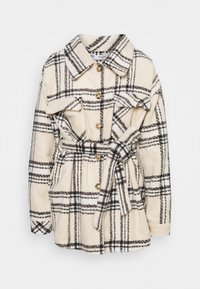 Krémovo-černý kostkovaný sako s páskem, knoflíky, klopovými náprsními kapsami a límečkem, vyrobené z měkké texturované látky.