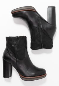 Zwarte enkellaarsjes met een mix van glad leer en suède, een detail met een rits aan de zijkant en een chunky, getextureerde hak. Geaccentueerd met een bruine zool.