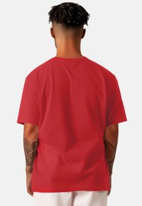T-shirt in cotone rosso con collo a giro standard, maniche corte e una superficie liscia senza motivi o dettagli visibili.