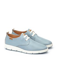 Zapatos de cuero perforado azul claro con cordones blancos, suela de goma y acentos en color tostado cerca del talón. Puntera redondeada y diseño minimalista.