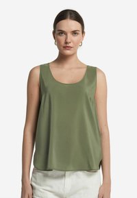 Top senza maniche verde oliva realizzato in tessuto morbido, con scollatura rotonda, vestibilità ampia e spacchi laterali per facilitare i movimenti.