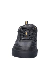 Zwarte sneaker met een leren bovenwerk met textuur, versterkte neus, platte zwarte zool, zwarte veters en gouden accenten op de tong en oogjes.