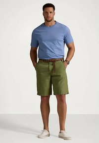 Ljusblå kortärmad t-shirt, gröna shorts, brunt bälte och vita sneakers. Avslappnad passform med solida färger och minimal detaljering.