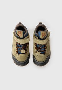 O pereche de botine pentru copii bej și albastre, cu vârfuri negre din cauciuc, șireturi maro și o curea cu velcro, văzute dintr-o parte de sus pe un fundal alb.