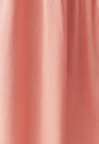 Jasnoróżowy materiał o gładkiej fakturze, lekko pomarszczony, prezentujący miękki spadek i jednolity kolor w całej powierzchni.