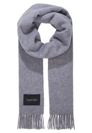 Lysegråt uldtørklæde med frynsete ender og et sort mærke med "Calvin Klein" skrevet med hvid tekst.
