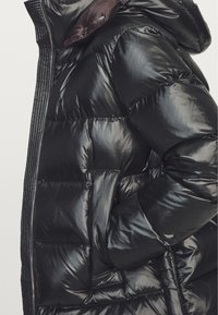Black puffer jacket features a glossy finish, zip closure, padded sections, and a hood, with side pockets integrated into the design.