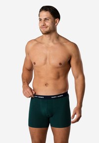 Donkergroene boxershorts van zacht materiaal, met een snug fit en een contrasterende zwarte tailleband met de tekst "HAPPY SHORTS".