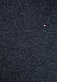 Tessuto a maglia grigio scuro con una superficie liscia, caratterizzato da un piccolo logo ricamato rosso, bianco e blu sul davanti.