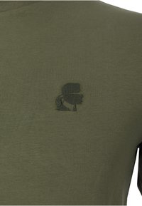 Olivgrünes Langarm-T-Shirt, leichtes Material, mit einem dezenten bestickten Logo auf der Brust, rundem Ausschnitt und tailliertem Design.
