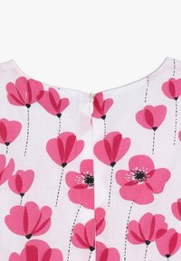 Blumenkleid mit einem hellen pinken Stoffhintergrund und kräftigen, mehrfarbigen Blumen in verschiedenen Rosatönen und Schwarz sowie einem Reißverschluss auf der Rückseite.