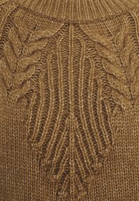 Pull en maille jaune moutarde avec un col rond côtelé, présentant un motif de feuilles et des détails en torsades texturées sur le devant.