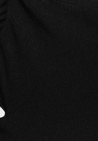 Detailní záběr na černou pletenou látku, která ukazuje jemnou žebrovanou strukturu a subtilní záhyby.