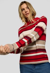 Roter und beiger gestreifter Strickpullover mit langen Ärmeln, ausgestattet mit gerippten Bündchen und einem Rundhalsausschnitt. Glatte Textur mit unterschiedlich breiten Streifen.