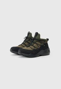 Black and olive green mid-top sneakers with streamlined design, textured fabric patterns, and black laces against a white background.