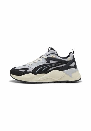Baskets basses de sport avec tige en mesh et suède blanc, noir et gris, semelle épaisse beige et languettes de traction sur la languette et le talon.