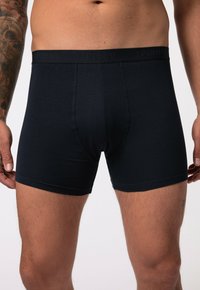 Schwarze Boxershorts aus weichem Stoff mit einem umschlagenen elastischen Bund, der das prägierte Markenlogo trägt. Enganliegendes Design mit nahtlosen Beinöffnungen.