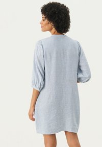 Robe en coton rayée, bleu clair et blanc, avec des manches bouffantes et un col rond. Texture lisse et design à mi-cuisse.