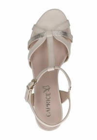 Sandalo beige con cinturini, dotato di un brillante accento argento sulla parte anteriore, cinturino alla caviglia regolabile e soletta imbottita. Nome del marchio "Caprice" impresso all'interno.