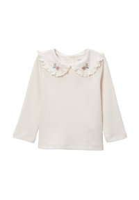 Chemise à manches longues couleur crème avec une texture côtelée, un col froncé et des accents de broderie florale sur le col.