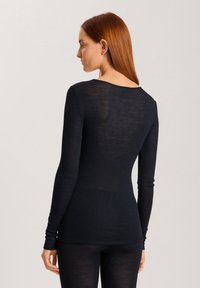 Maglietta nera a maniche lunghe in maglia con scollatura a barca, realizzata in un tessuto leggero e leggermente trasparente, con maniche aderenti e un design sagomato.