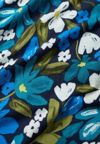 Floral fabric with varying shades of blue, white, and green flowers on a dark navy background; features bold leaves and a textured appearance.