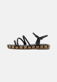 Sandales noires à brides avec des détails tressés, bride de cheville ajustable et une semelle épaisse et texturée avec un motif tressé.
