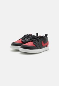 Sorte og røde lædersneakers med en struktureret overflade, featuring en hvid gummisål, sorte snørebånd og et fremtrædende rødt logo på siden.