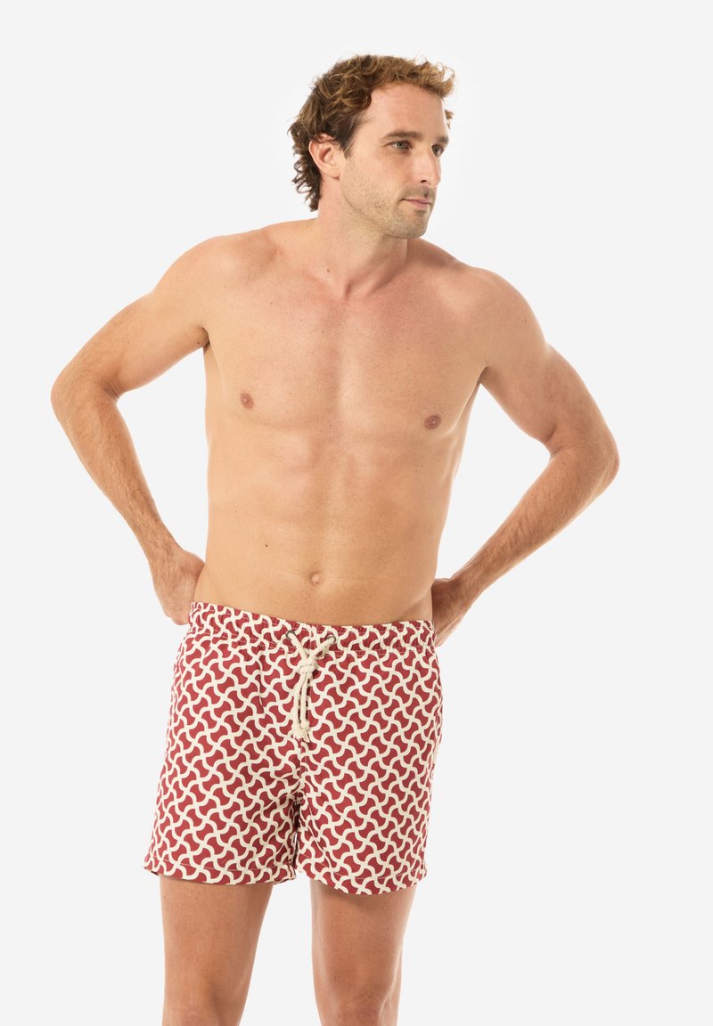 Costumi da bagno rossi con un motivo a onde bianche, dotati di una cintura con cordino. Il tessuto appare leggero e traspirante.