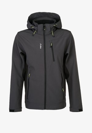 Homme portant une veste à capuche gris foncé et un pantalon de plein air orange vif et noir avec des chaussures de randonnée noires, debout devant un fond uni.