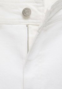 Beli denim zadrga s srebrnim kovinskim gumbom z oznako "MNG JEANS." Tkanina ima gladko teksturo in je brez okrasnih elementov.
