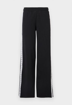 Μαύρο παντελόνι με φαρδιά μπατζάκια, ελαστική μέση και λευκές ρίγες σαν δαντέλα που τρέχουν κατά μήκος κάθε πλευρικής ραφής.