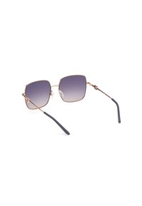 Occhiali da sole quadrati con lenti grigie sfumate, una sottile montatura in metallo color oro rosa e aste in plastica grigio scuro con morbidi naselli in silicone trasparente.