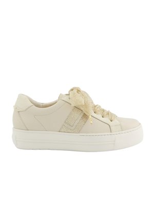 Low-top beige sneaker with thick white sole, textured fabric side stripe, and wide glittery cream-colored laces tied in a bow.