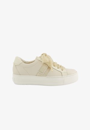 Beige Low-Top-Sneaker mit dicker weißer Sohle, strukturiertem Stoff-Seitenstreifen und breiten glitzernden cremefarbenen Schnürsenkeln, die zu einer Schleife gebunden sind.