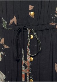 Zwarte jurk met een bloemenpatroon in beige en groene tinten. Bevat gouden knopen, een elastische tailleband en een trekkoorddetail.