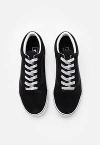 Sneakers in suede nero con suole in gomma bianca, dotate di lacci argentati e una texture liscia. Punta arrotondata e linguetta imbottita per il comfort.