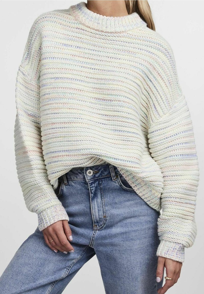 Överdimensionerad stickad tröja i pastellfärger med horisontella ränder, en ribbad halsringning och breda ärmslut, parat med ljusblå denimjeans.