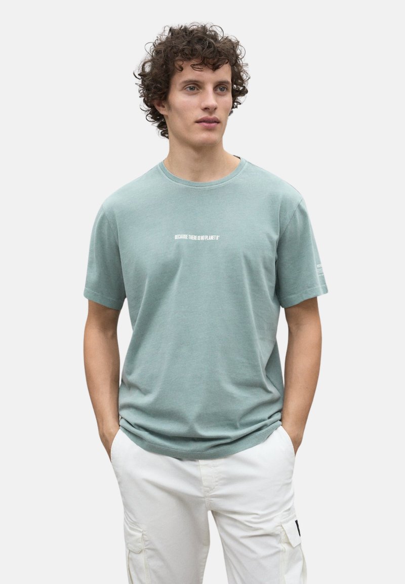 Camiseta de algodón verde claro con mangas cortas, cuello redondo y texto blanco que dice "PORQUE NO HAY UN PLANETA B" en el pecho.
